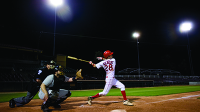 A baseball player hitting a ball while the umpire and the catcher are behind him 