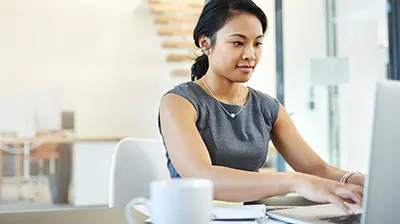 A woman working at a desk on a laptop computer