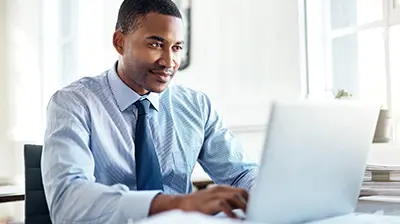 A man working at a desk on a laptop computer