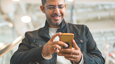 A man smiling down at his smart phone while holding it in both hands