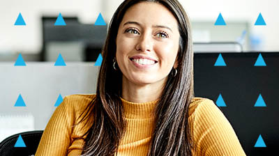 A woman in an orange sweater smiling and looking off to the right
