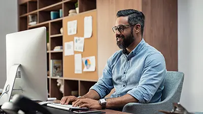 Man at desk typing at a computer.