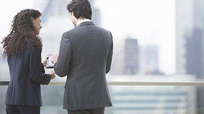 Business Woman and Business Man looking at a tablet on a rooftop
