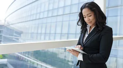 A woman standing outside using a tablet
