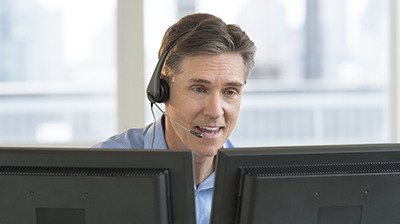 A man wearing a headset sitting at his computer