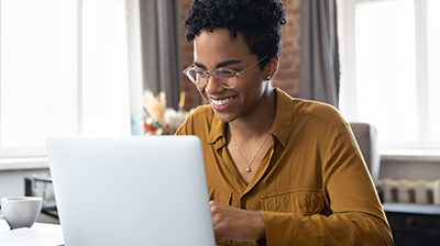 A woman smiling down at her open laptop 