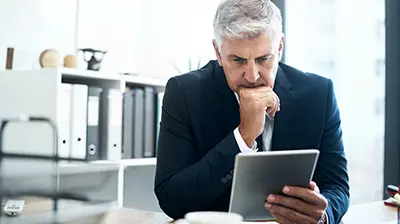 A focused businessman looking at a tablet in his hand