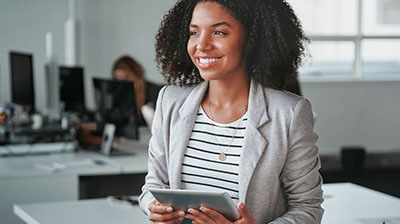 A business woman holding a tablet while smiling off to the side 