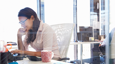 A young woman sitting at her desk working on a laptop