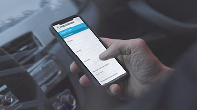 A hand using a smart phone while inside a car. 
