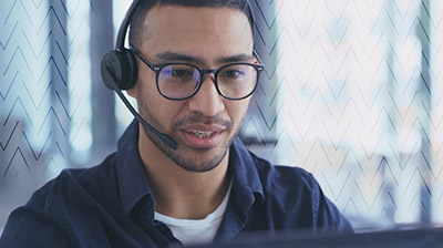 A man wearing a headset while sitting in front of a computer 