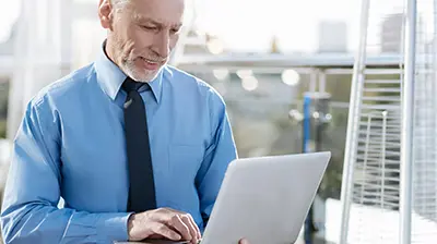 A businessman working on his laptop on the roof of a building