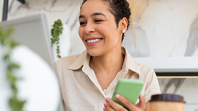 A woman smiling off to the left while holding a green cell phone in one hand 