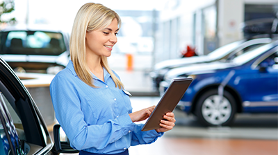 A young woman at a car dealership looking at a tablet